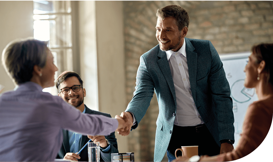 Business coworkers shaking hands during a meeting in the office. Focus is on a businessman.